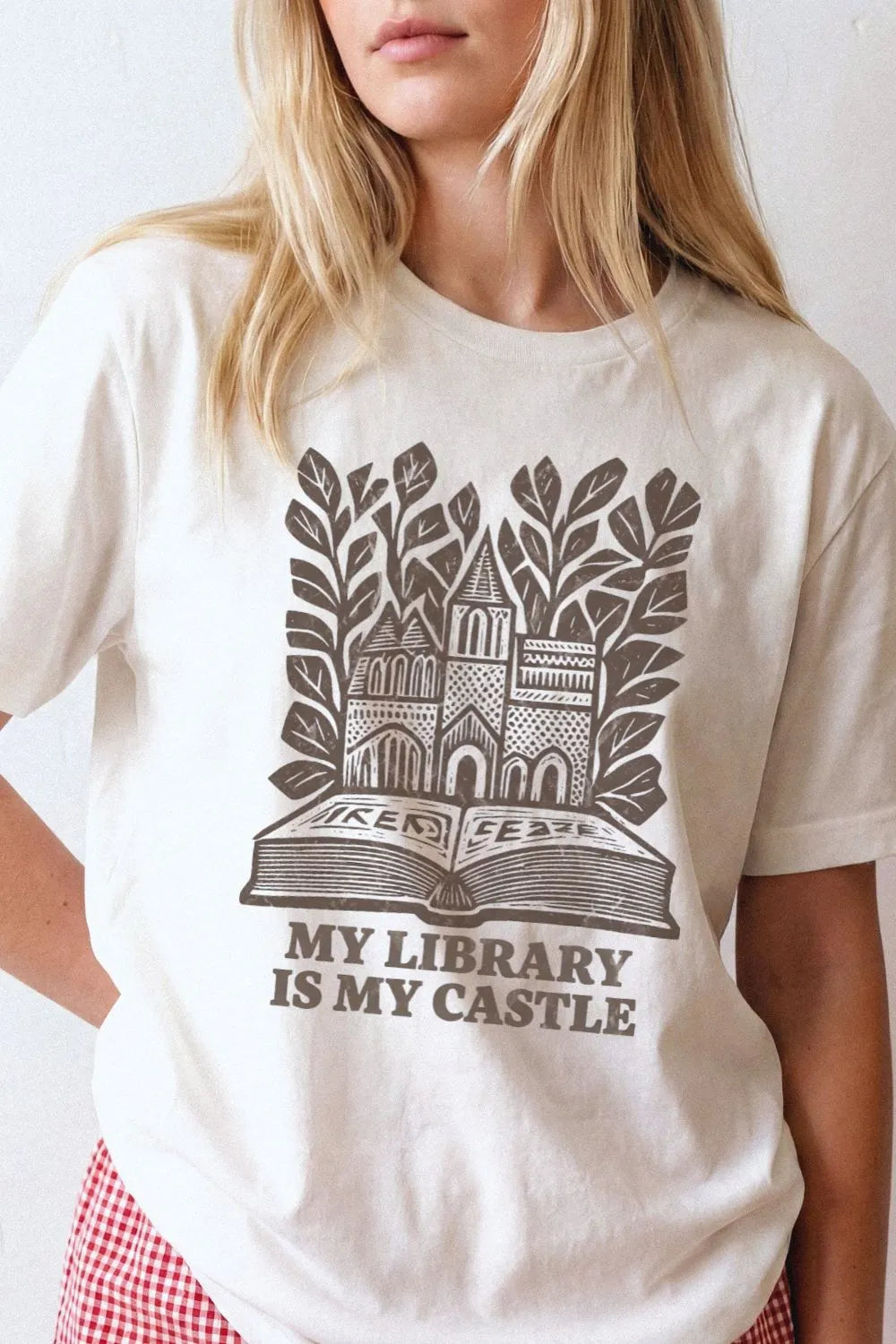 woman wearing natural beige  literary t-shirt with “My Library Is My Castle” design featuring books and castle illustration, styled as cozy librarian aesthetic outfit