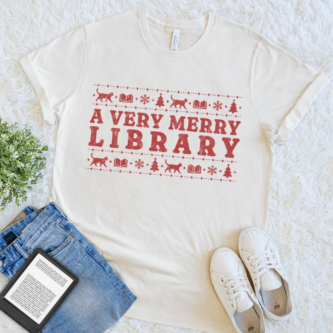 Natural book lover holiday tee with distressed red A Very Merry Library artwork and playful reading cats