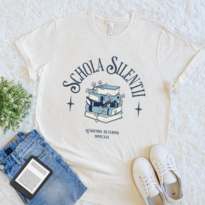 natural beige bookish T-shirt with Schola Silentii text and stacked books illustration in dark academia style
