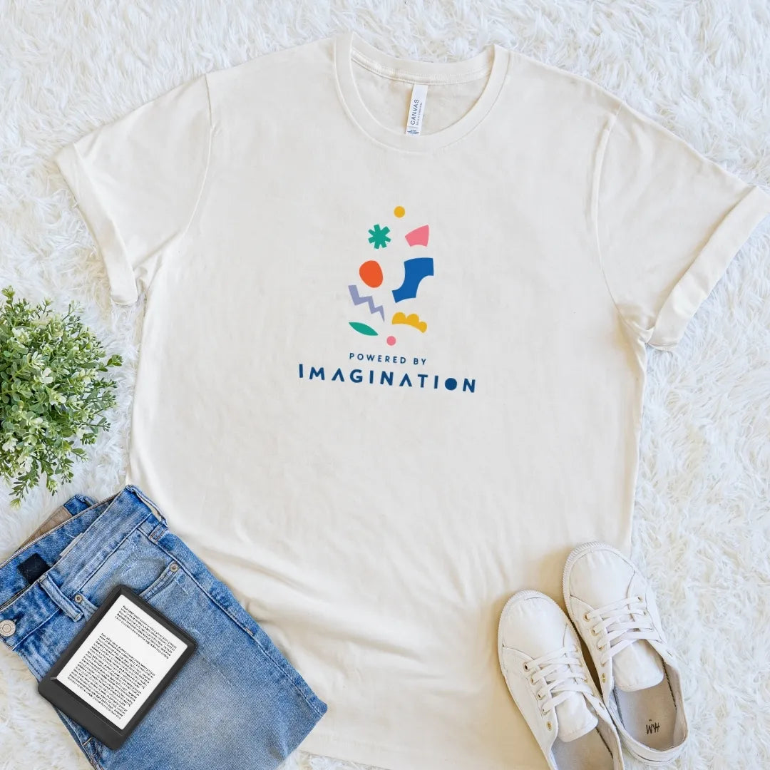 Natural Powered by Imagination reader T-shirt with colorful abstract shapes and playful typography, a modern bookish shirt celebrating a vivid inner world.
