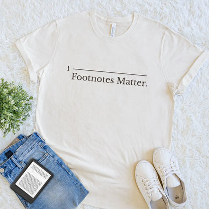 Cream book lover T-shirt with academic humor footnote graphic