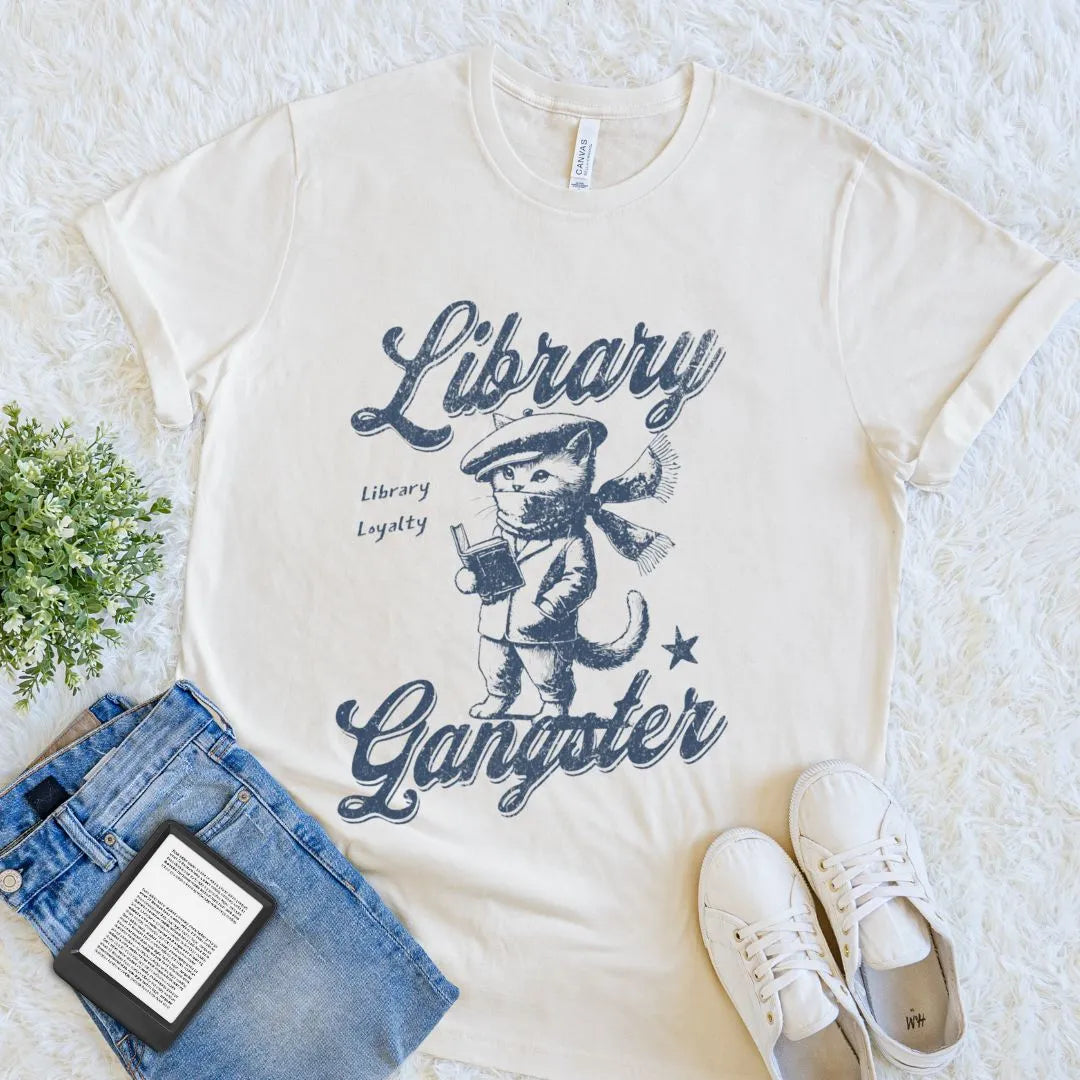 Soft cotton natural beige t-shirt with vintage gangster kitten reading open book illustration and quote "Library gangster library loyalty" 