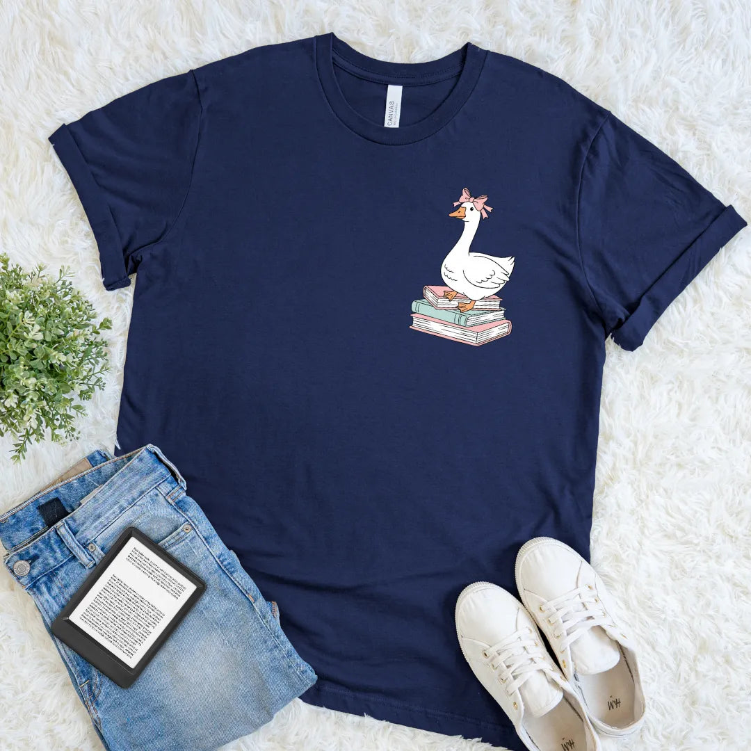 Navy blue t-shirt with a bookish silly goose design on a white surface with jeans and sneakers.