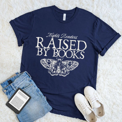 Bookish t-shirt with 'Nights Readers Raised by Books' text and butterfly graphic on navy blue cotton