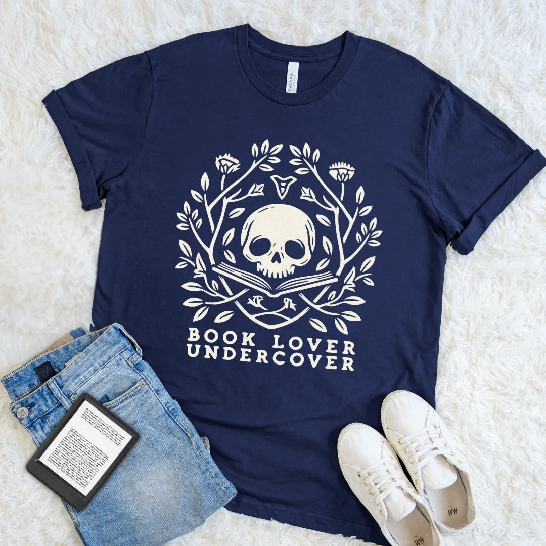 Navy book lover graphic shirt with an ivory skull-and-book emblem for readers drawn to gothic literary style
