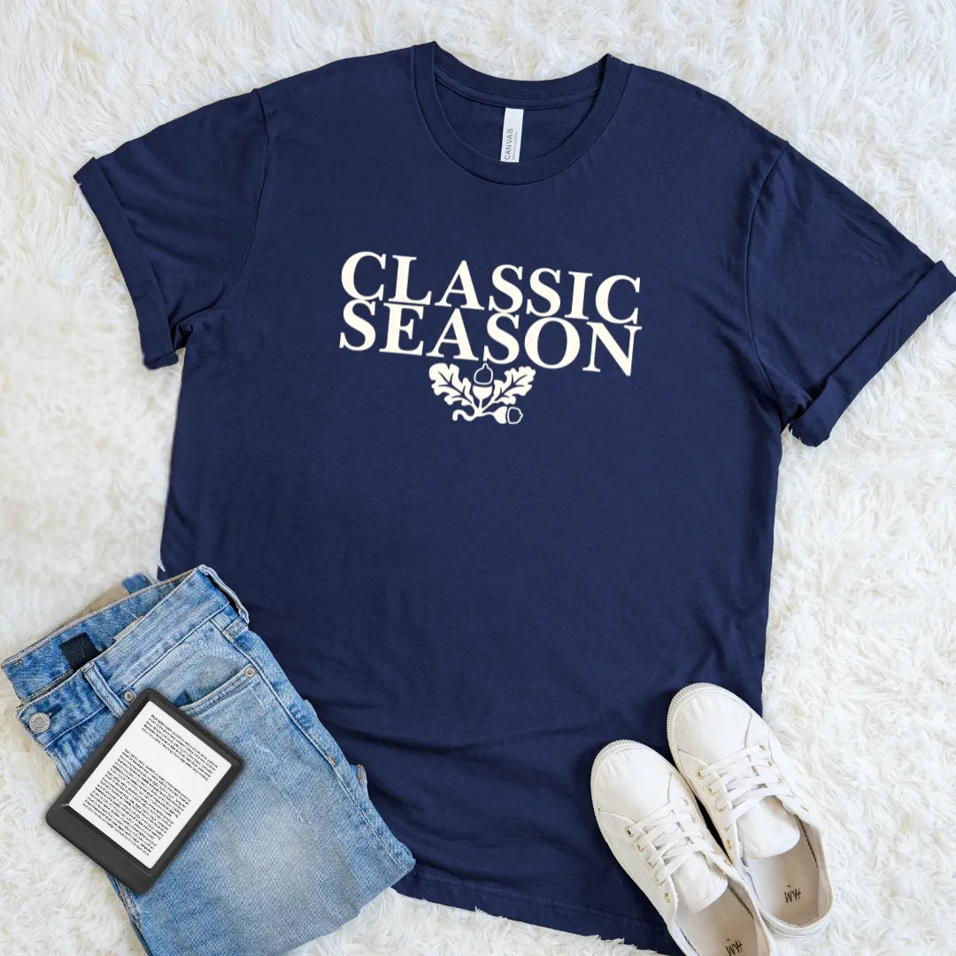 Navy Classic Season reader T-shirt with cream vintage serif lettering and autumn oak details, a cozy literary graphic tee for habitual rereaders.