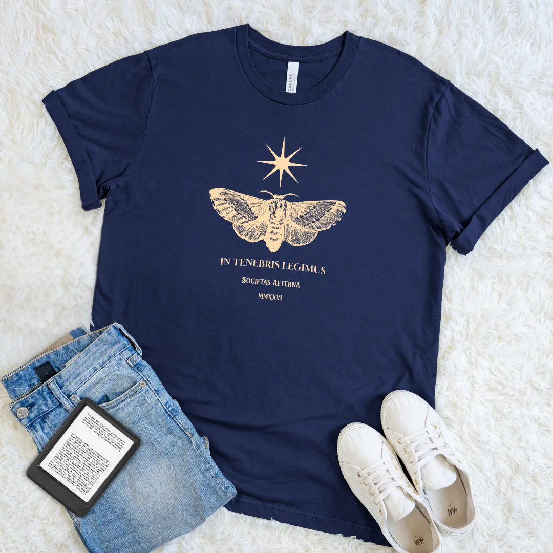 Soft cotton navy t-shirt featuring latin  quote "we read in dark" in golden typography  and vintage moth and stars design 