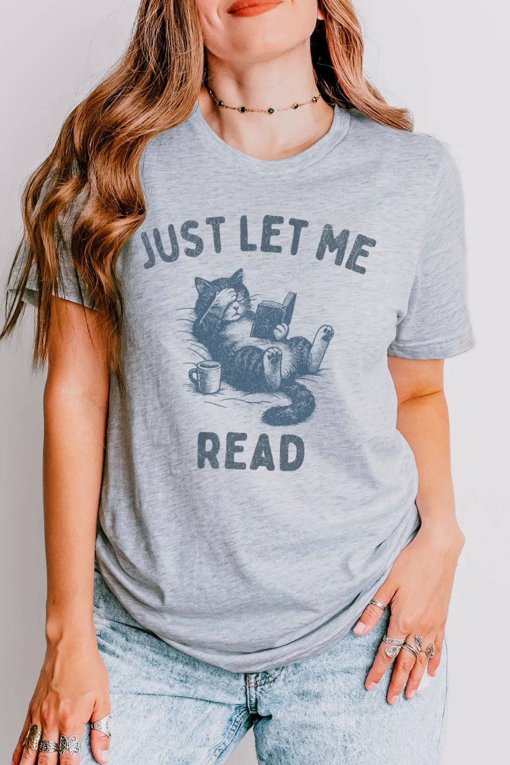 woman wearing heather gray T-shirt with cat reading a book and holding a coffee mug design and "Just let me read" quote