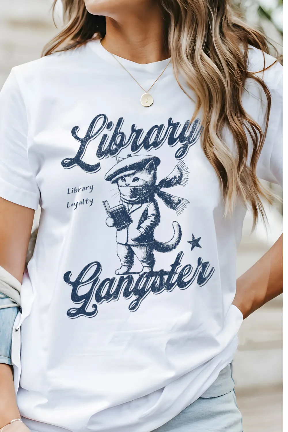 woman wearing white T-shirt with vintage cat in beret reading a book and "Librarty Gangster" quote