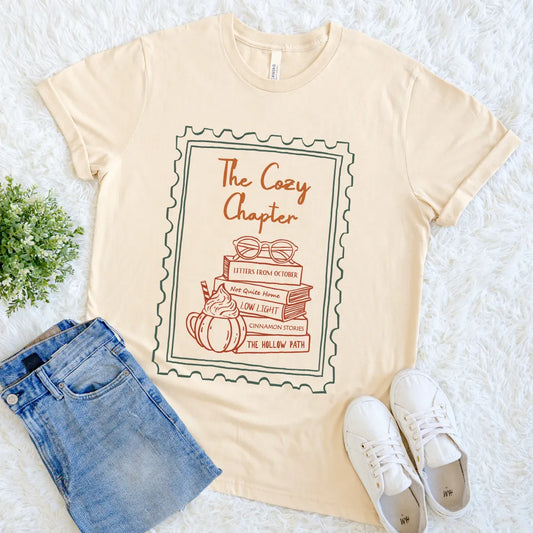 Cream T-shirt with book stack and cozy chapter pumpkin spice design
