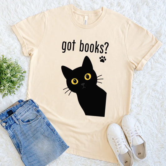 Cream  tee featuring a yellow-eyed cat and paw print above text