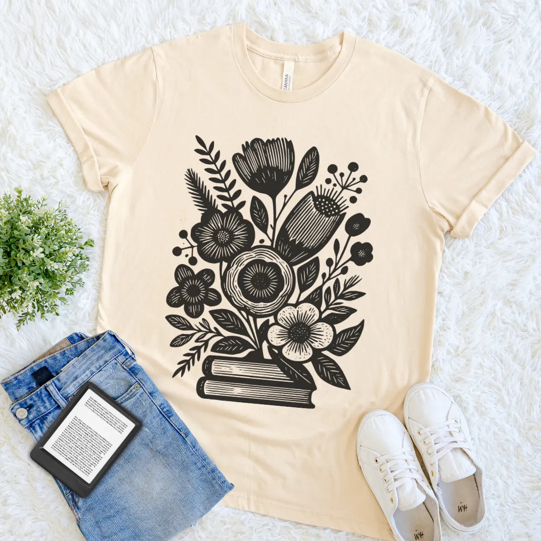 Soft cream book lover T-shirt with black floral bouquet growing from stacked books woodcut illustration