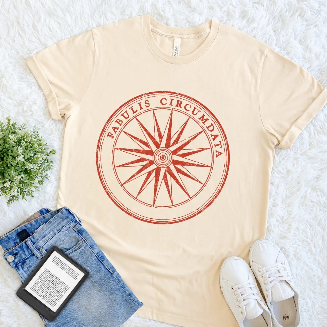Soft Cream Fabulis Circumdata T-shirt with a weathered compass rose and Latin phrase meaning surrounded by stories