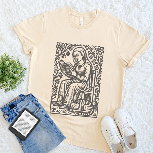 Flat lay of soft cream book lover T-shirt with vintage woman reading and sleeping cat illustration