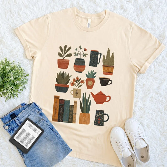 Soft cream cotton bookish T-shirt featuring illustrated houseplants, books, mugs, and a red teapot