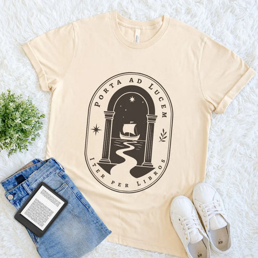 Soft cream book lover T shirt featuring an arched portal with a ship and Latin literary design
