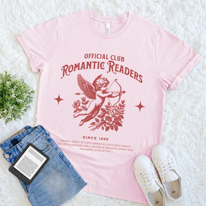 Pink t-shirt with 'Official Club Romantic Readers' design on a white surface with jeans and sneakers.