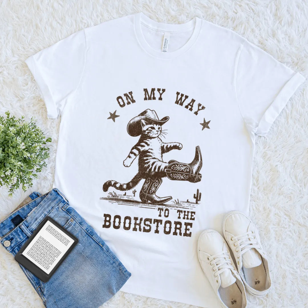 Flat lay of white soft cotton quirky literary tee with cowboy-themed cat illustration 