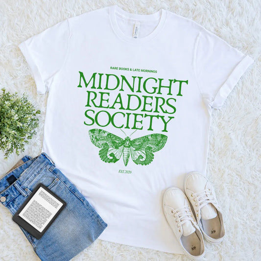 Soft cotton white t-shirt with green moth design and "midnight readers society" text, styled with denim  and e-reader on light background