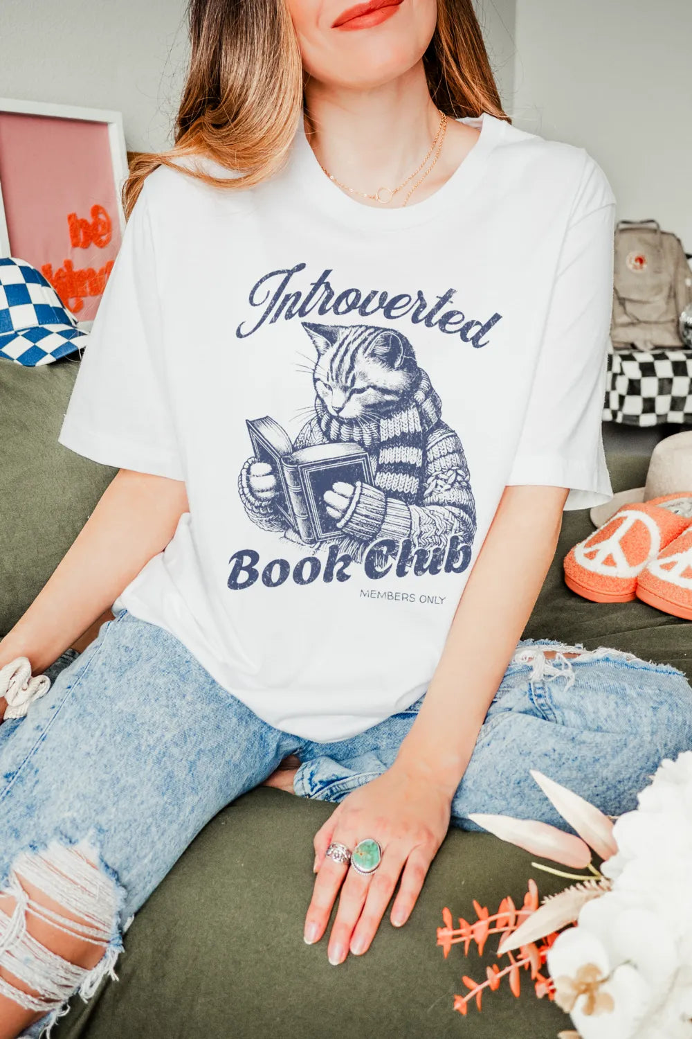 woman wearing white T-shirt with vintage cat reading a book and “Introverted Book Club” quote