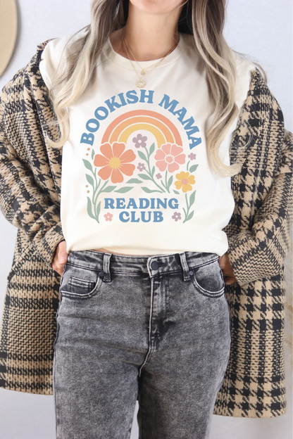 woman wearing cream T-shirt with pastel rainbow, flowers, and “Bookish Mama Reading Club” text