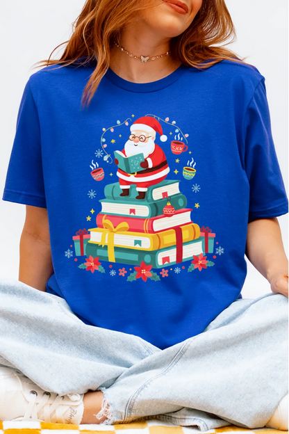 woman wearing a royal blue t-shirt with a colorful Christmas design of Santa Claus reading books and mugs.
