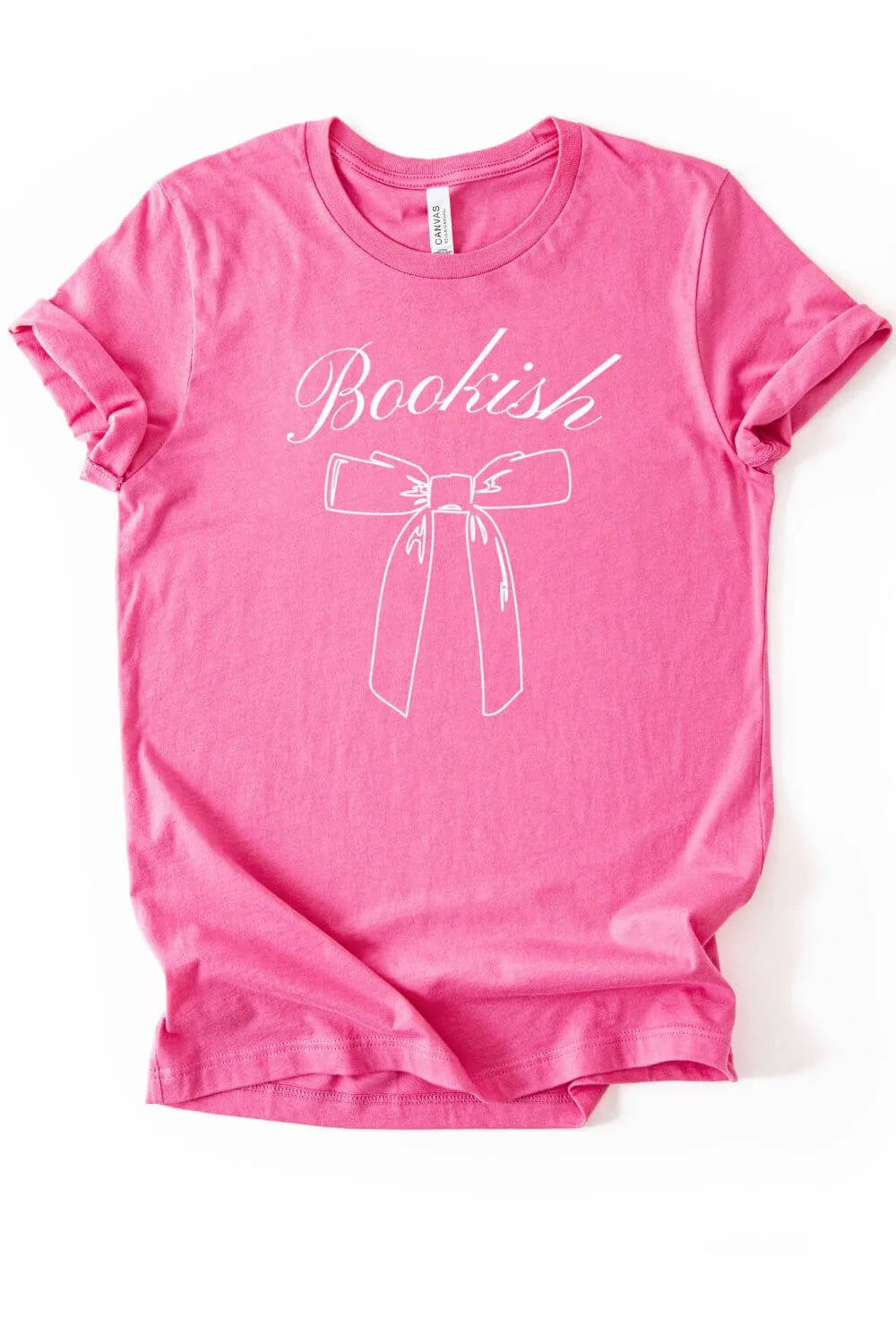 A bright pink soft cotton graphic t-shirt featuring the word “Bookish” in elegant script above a simple bow illustration in white.