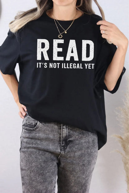 woman wearing black T-shirt with bold white text saying “Read – It’s not illegal yet”