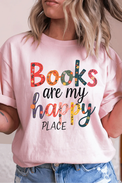 woman wearing soft pink T-shirt with colorful floral text reading “Books are my happy place”