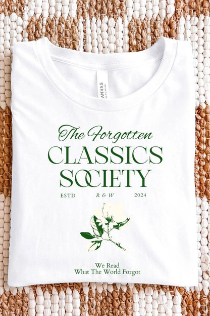 White soft cotton  t-shirt with dark green serif typography reading “The Forgotten Classics Society” and a vintage botanical illustration in a dark academia aesthetic, folded on textile surface