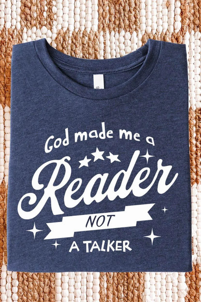 A soft heather navy blue t-shirt with white vintage-style text reading “God Made Me a Reader Not a Talker,” folded on textile surface