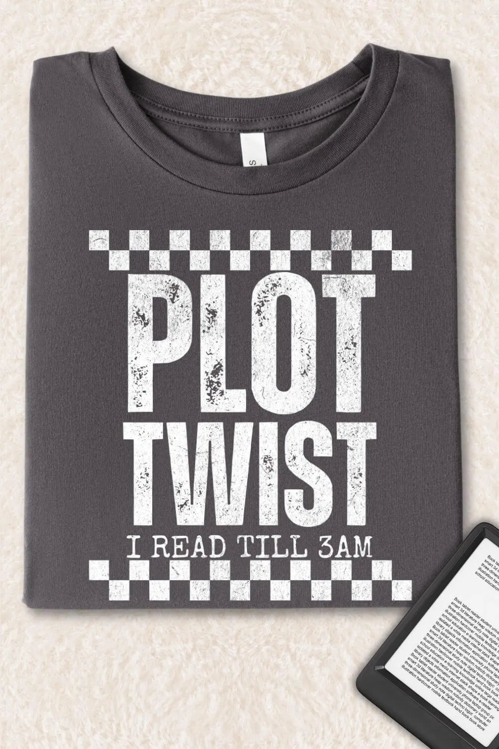 Folded  asphalt gray bookish T-shirt with distressed white text “Plot Twist – I Read Till 3AM”