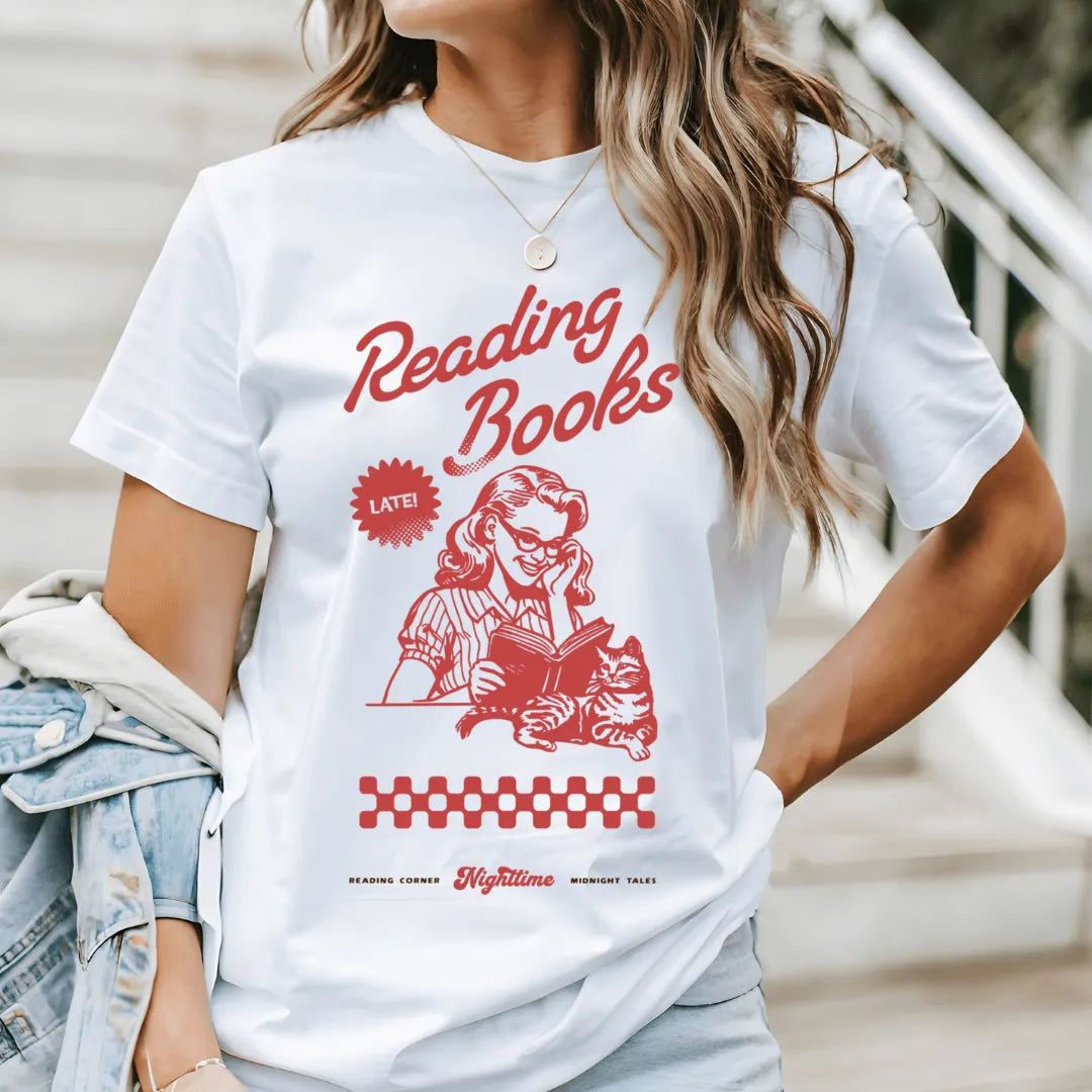 woman wearing white vintage soft cotton bookish tee for night readers with retro design featuring woman reading book and a cat