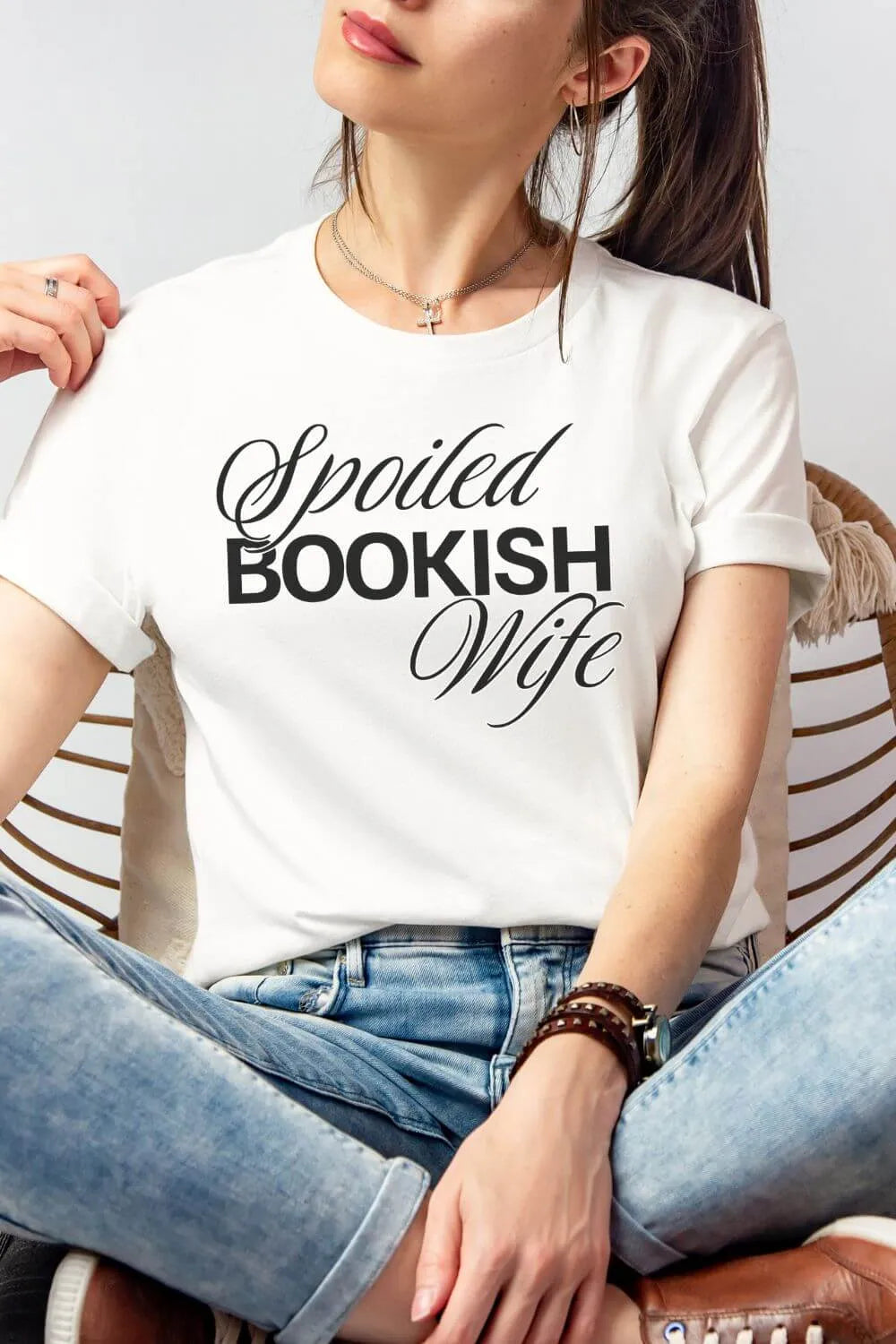 Woman wearing a white soft cotton t-shirt with 'Spoiled BOOKISH Wife' text.